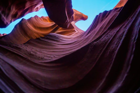 Blue sky framed by flowing purple sandstone walls in Antelope Canyon