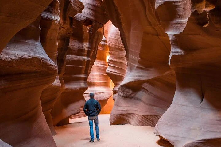 Traveler walking through the sculpted sandstone passage of Lower Antelope Canyon