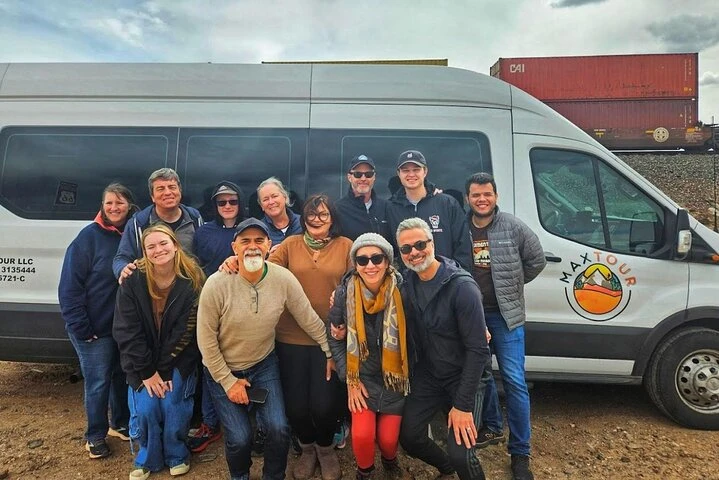 Small tour group standing beside the day-trip passenger van